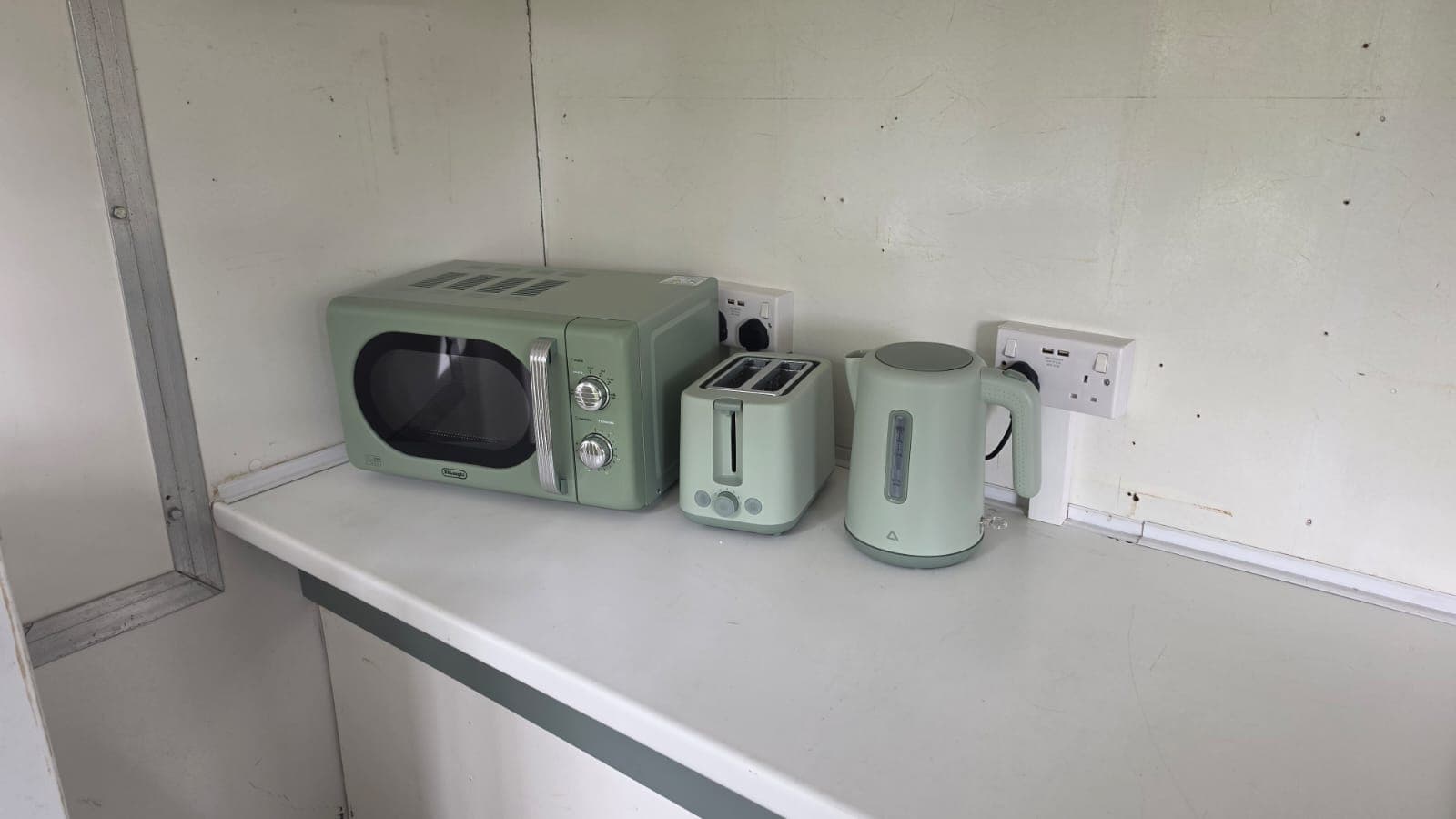 Sage green microwave, toaster and kettle on the trailer worktop.